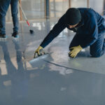 The worker applies gray epoxy resin to the new floor